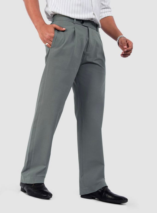 Man wearing slate grey relaxed fit pleated trousers with a white striped shirt and black dress shoes.