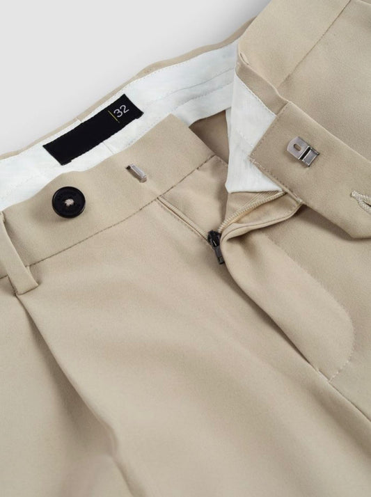 Close-up of men's khaki pleated trousers, showing pleats, pockets, and a button closure.