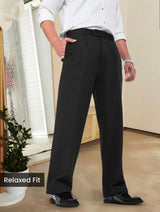 Man wearing black relaxed fit pleated pants with belt loops and side pockets.