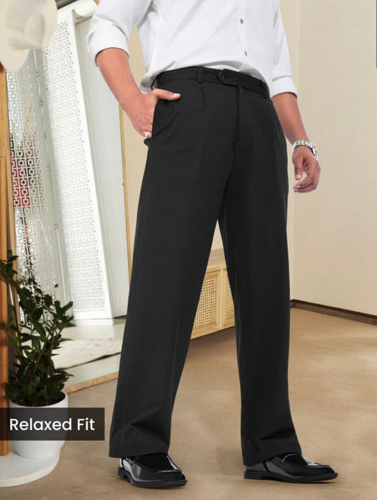 Man wearing black relaxed fit pleated pants with belt loops and side pockets.