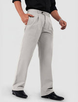 Man wearing light grey relaxed fit pleated trousers with a black shirt and dress shoes, standing indoors