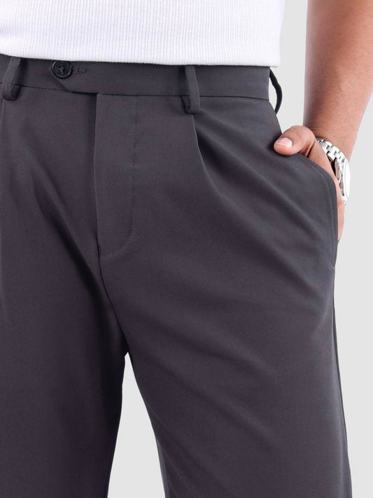 Close-up view of men's charcoal gray wide-leg pleated trousers with a visible button and zipper closure, and pockets.