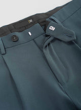 Man wearing teal relaxed fit trousers with loafers and a striped shirt.