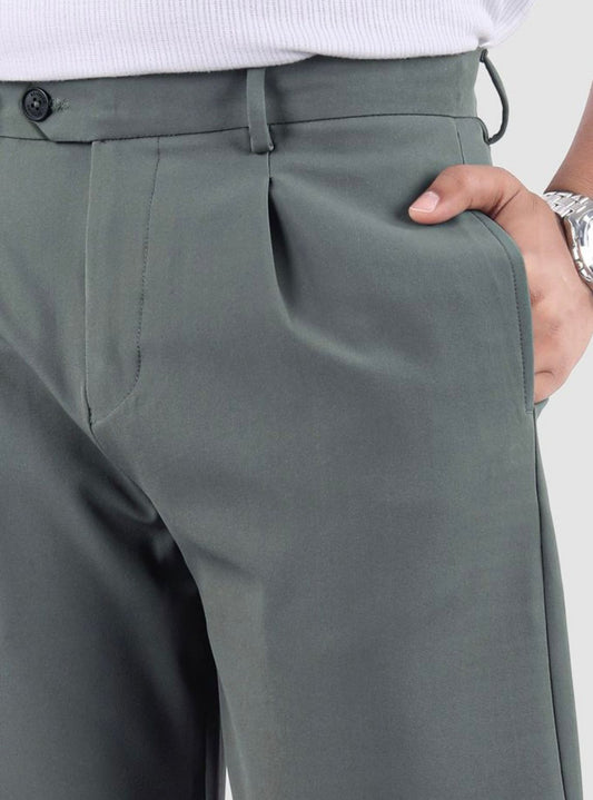 Man wearing sage green relaxed fit pleated trousers with a white striped shirt and black shoes.