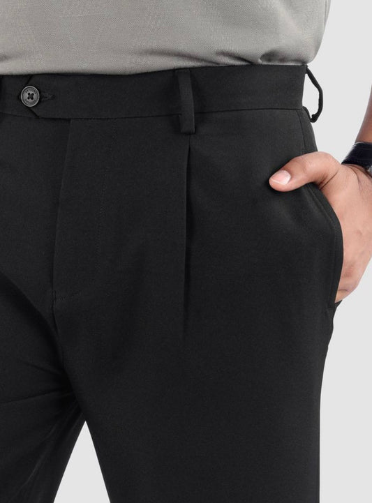 Man wearing black relaxed fit pleated pants with belt loops and side pockets.