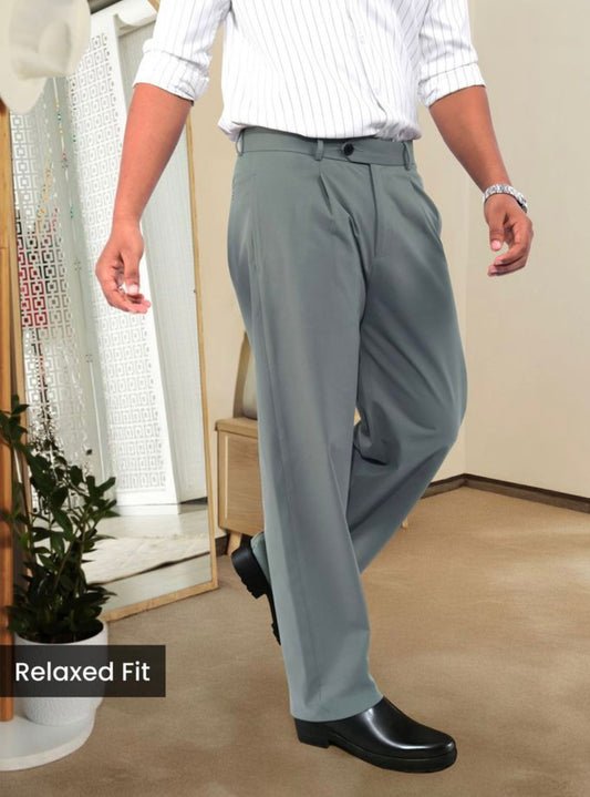 Man wearing slate grey relaxed fit pleated trousers with a white striped shirt and black dress shoes.
